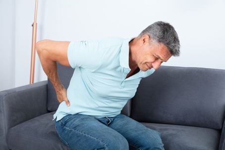 Man grimacing in pain and clutching his back